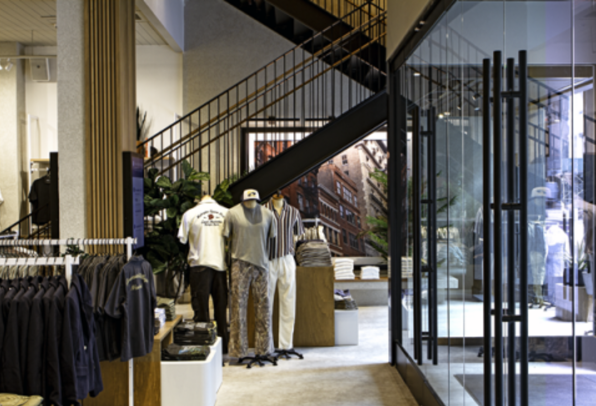 A store filled with clothes and mannequins and a staircase.