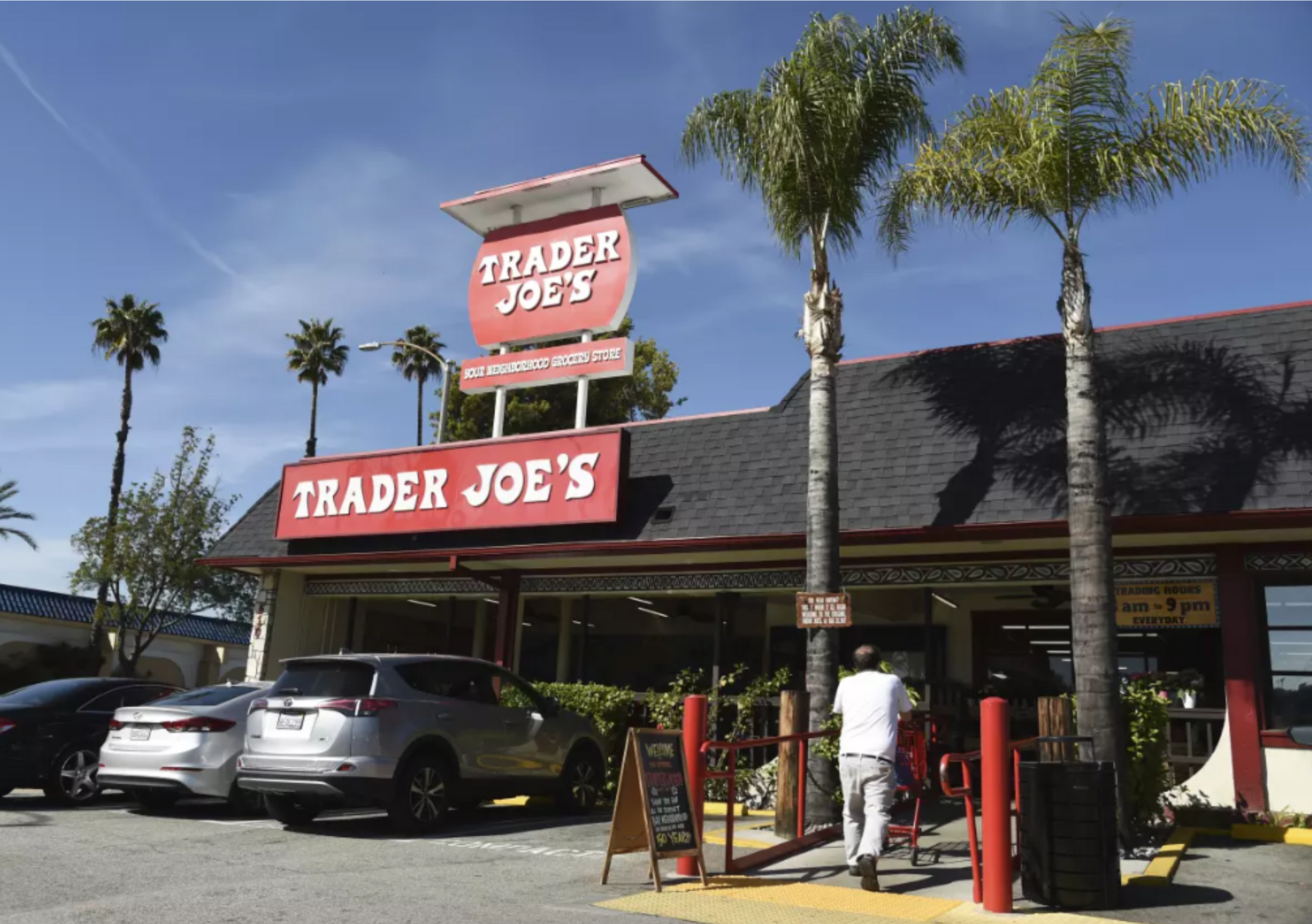 A trader joe 's restaurant with cars parked in front of it