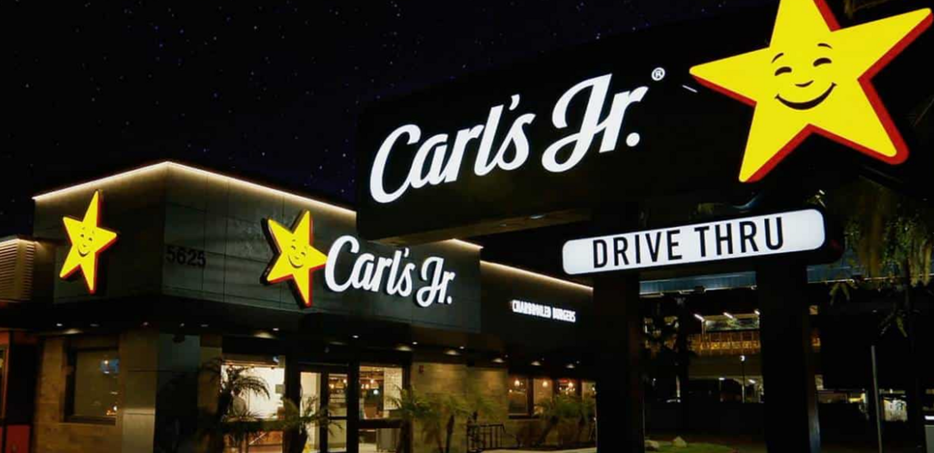A carl 's jr. drive thru sign is lit up at night