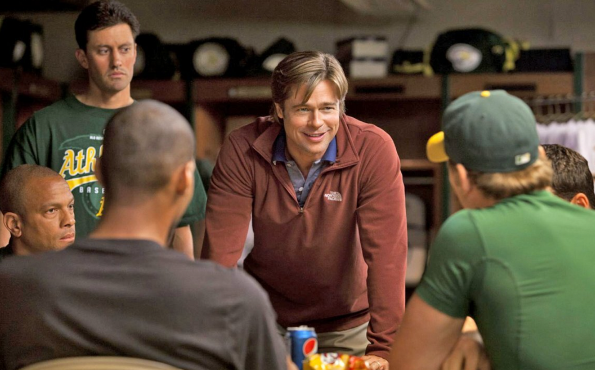 A group of men are sitting around a table talking to each other.