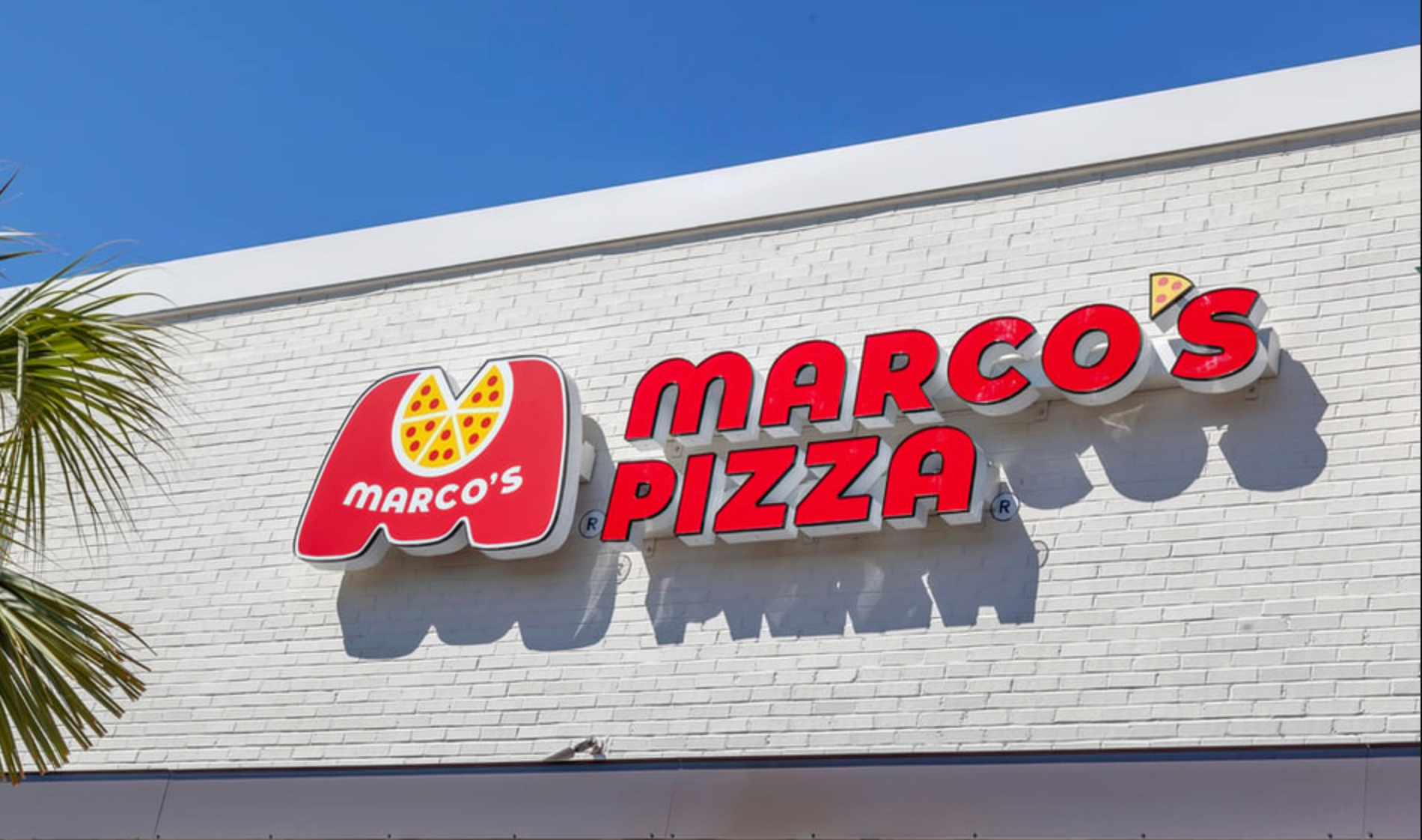 Interior of a casual restaurant featuring blue chairs, red accents, brick walls, and a