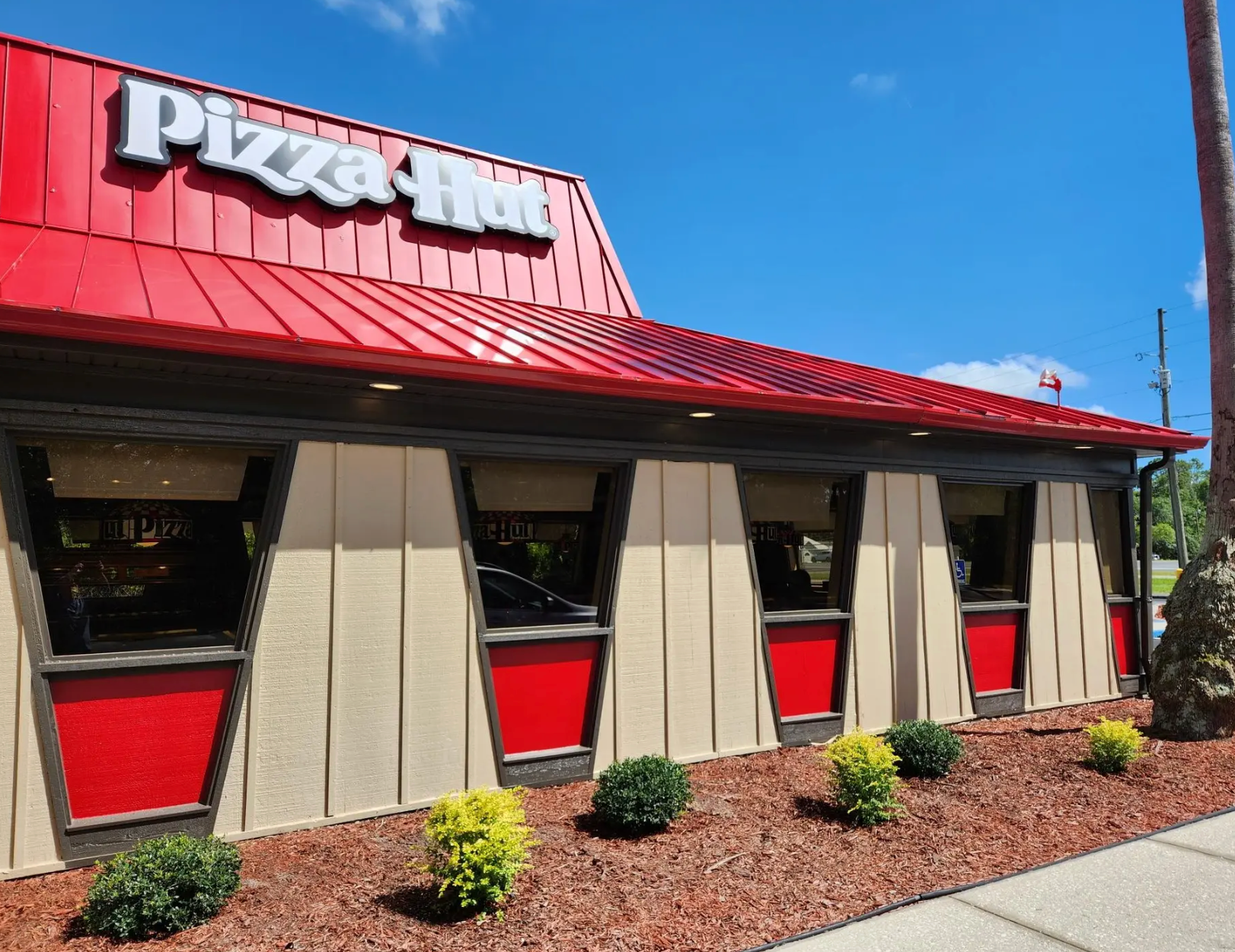 Interior of a casual restaurant featuring blue chairs, red accents, brick walls, and a