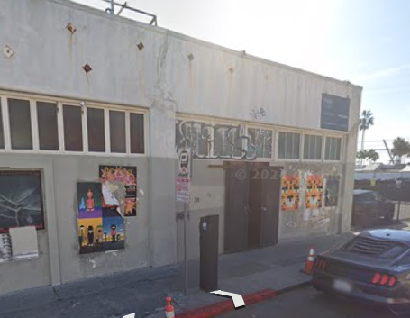 A car is parked in front of a building with the number 202 on it