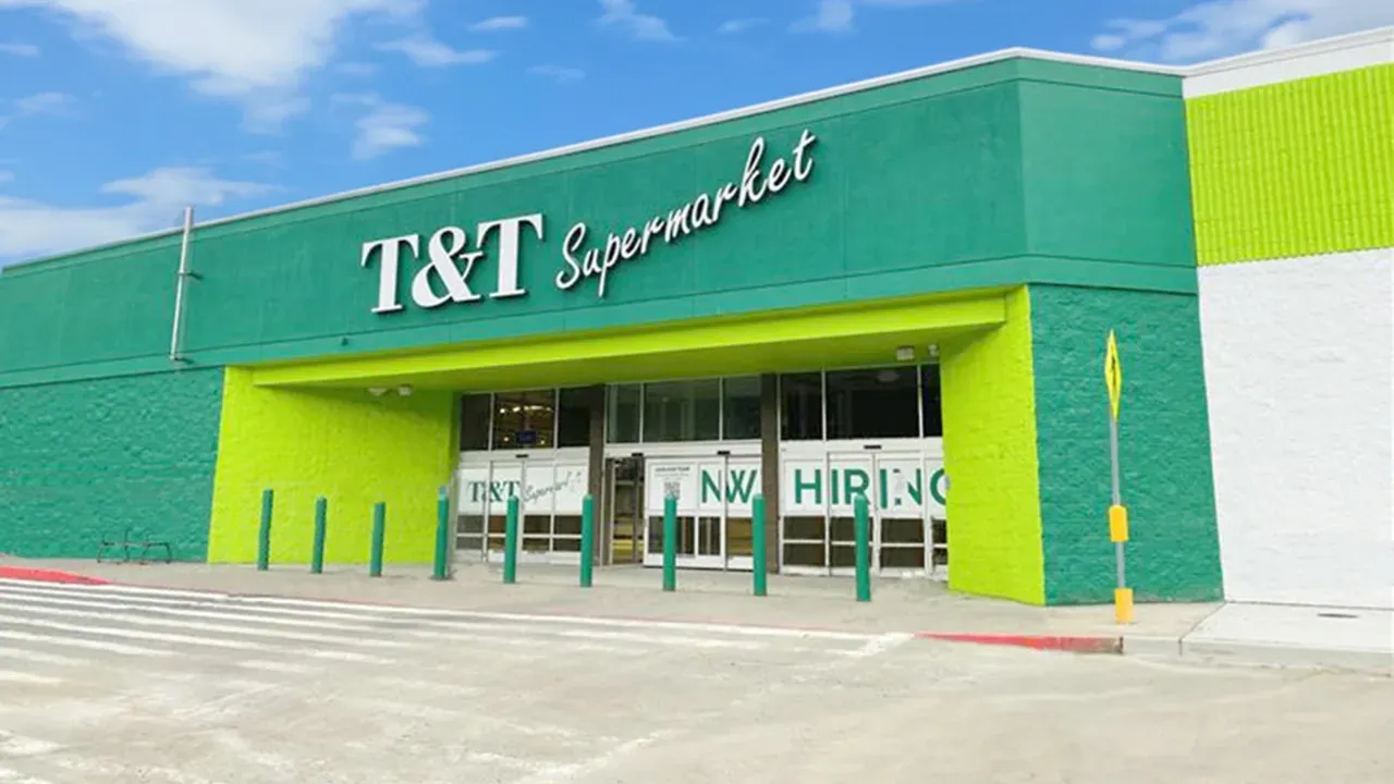 A green and white t & t supermarket with a parking lot in front of it