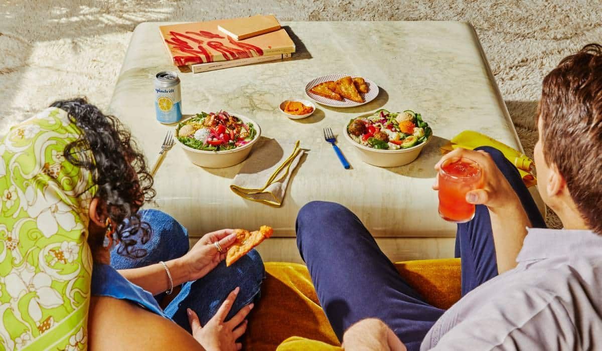 A man and a woman are sitting at a table eating food.