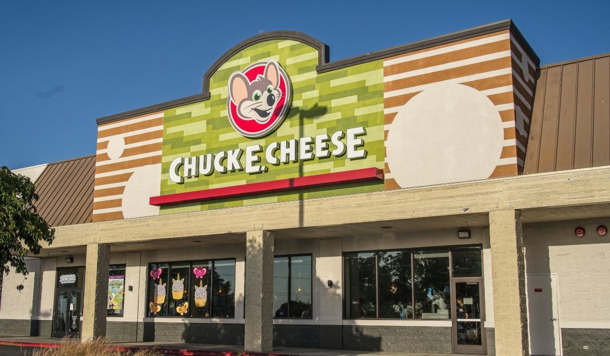 The front of a chuck e cheese restaurant with a mouse on the sign.