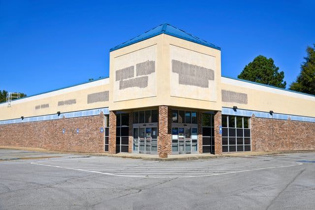 An empty store with a parking lot in front of it.