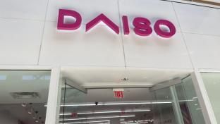 The front of a daiso store with a pink sign on it.