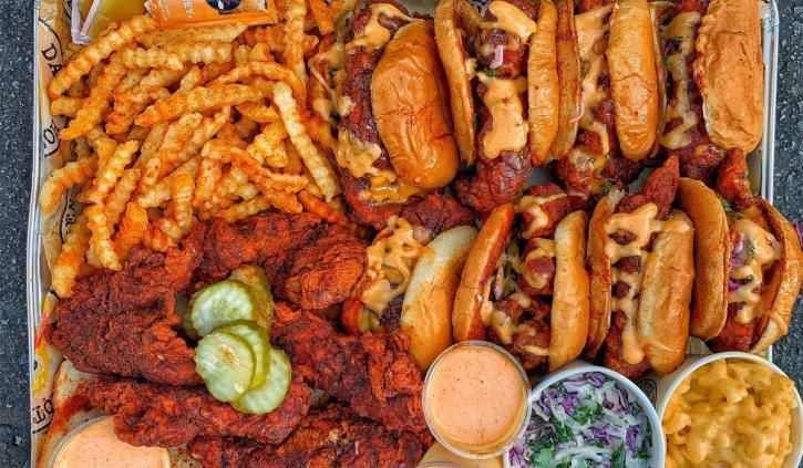 A large tray of fried chicken , hot dogs , french fries , macaroni and cheese , and pickles.