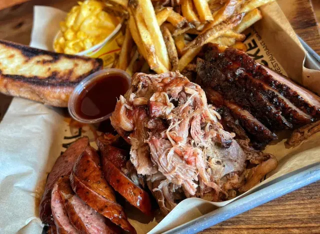 A plate of meat and french fries on a wooden table.