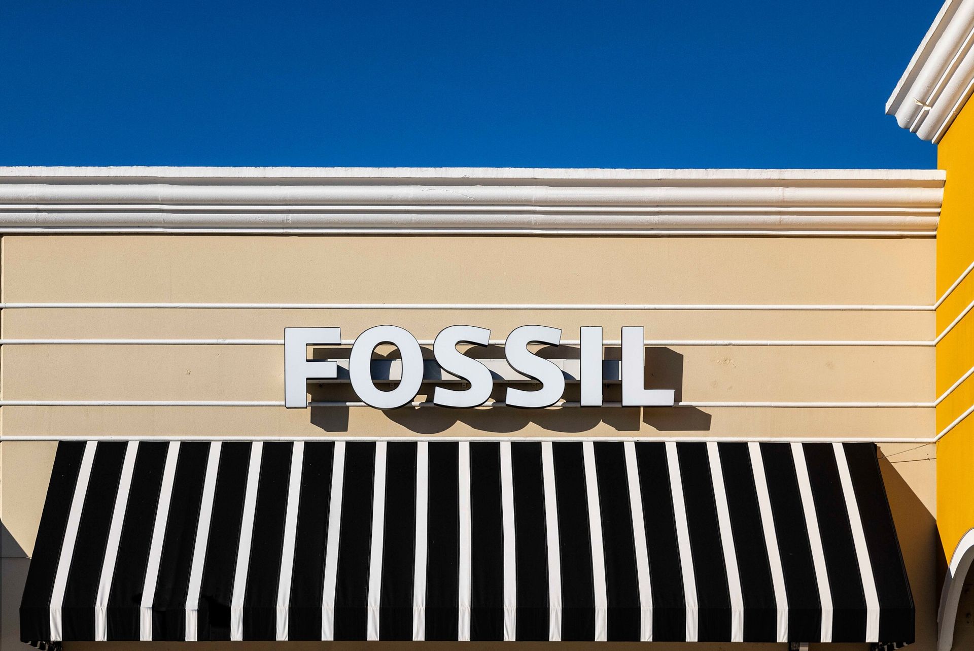 The front of a fossil store with a black and white awning.