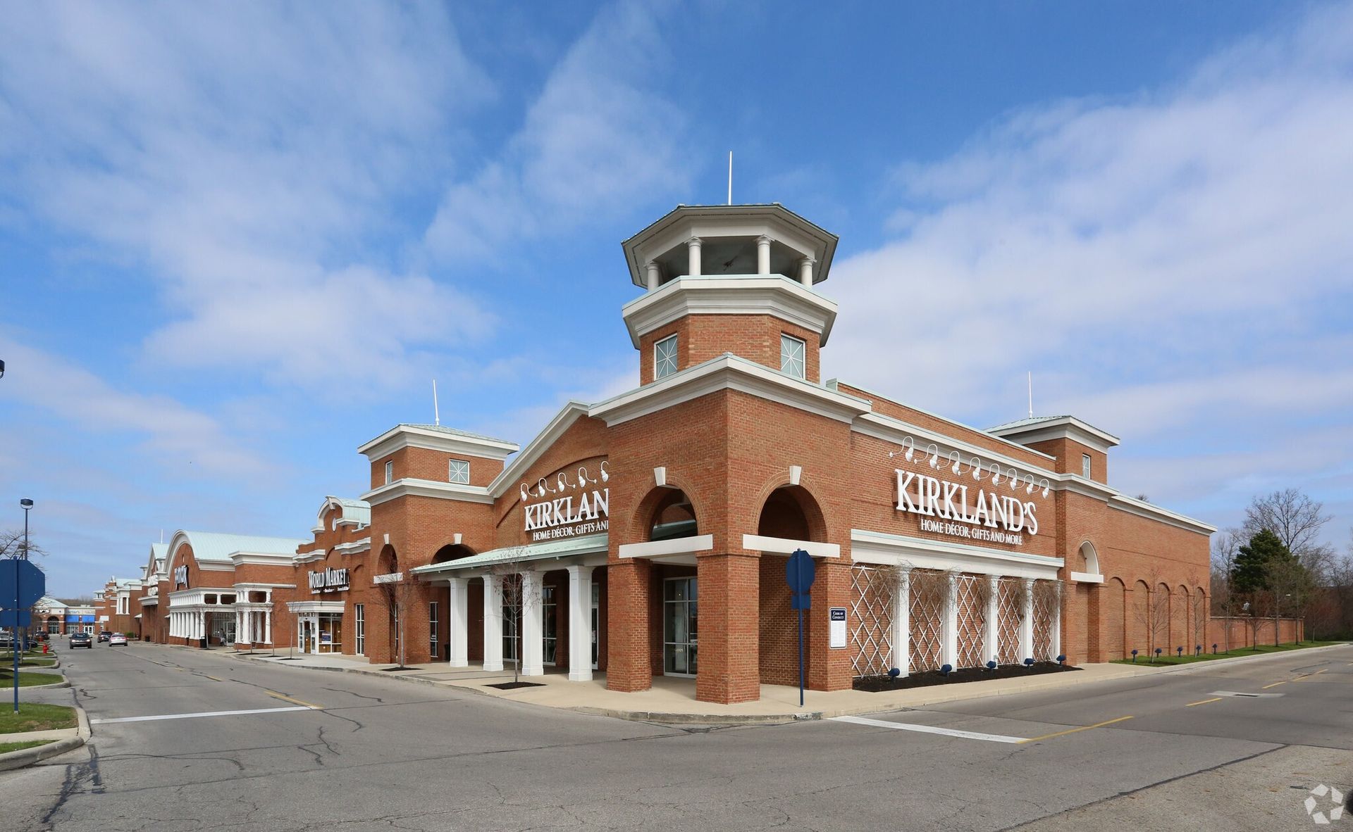 A large brick building with a tower on top of it is on the corner of a street.