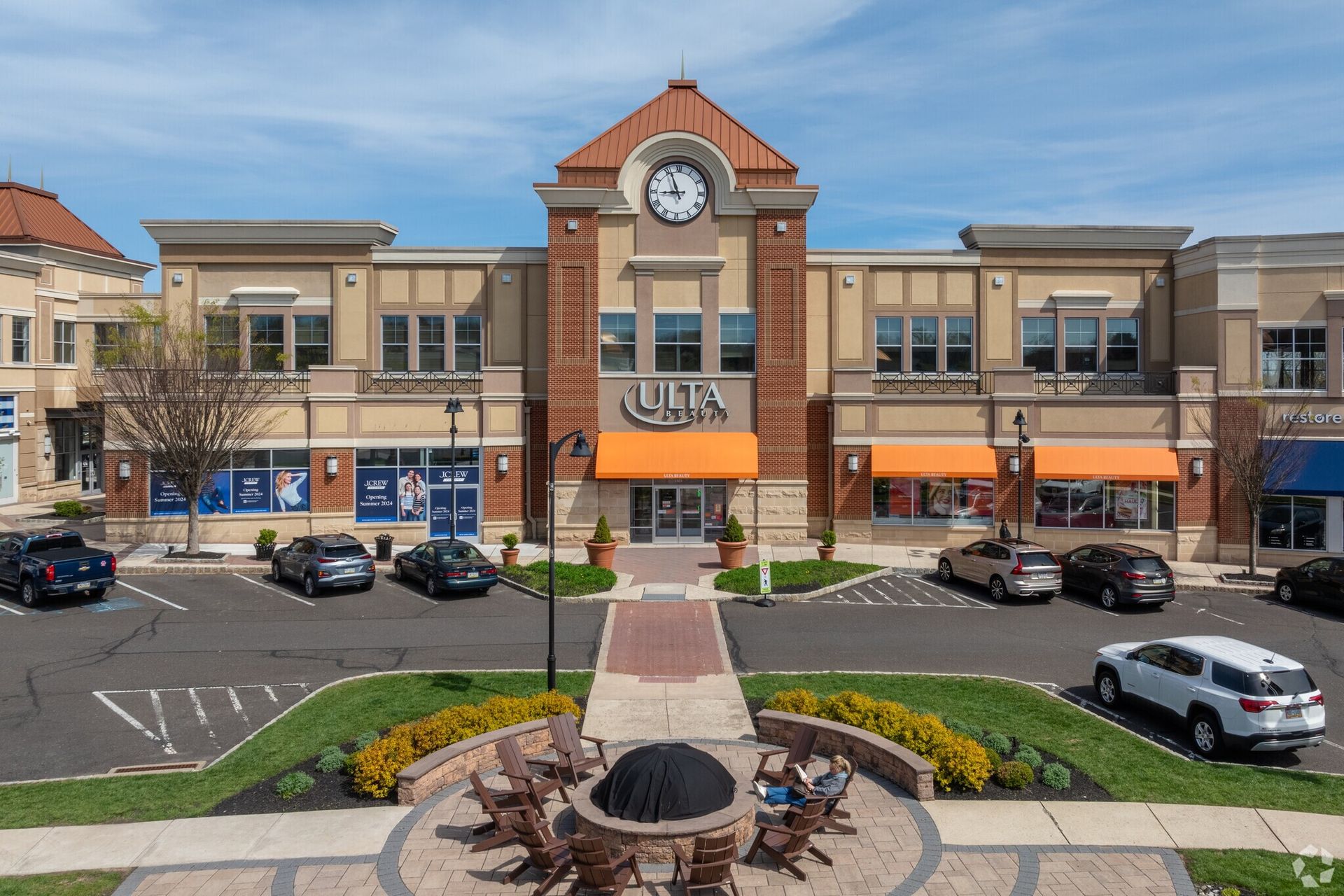 A large building with a clock tower and a fire pit in front of it.
