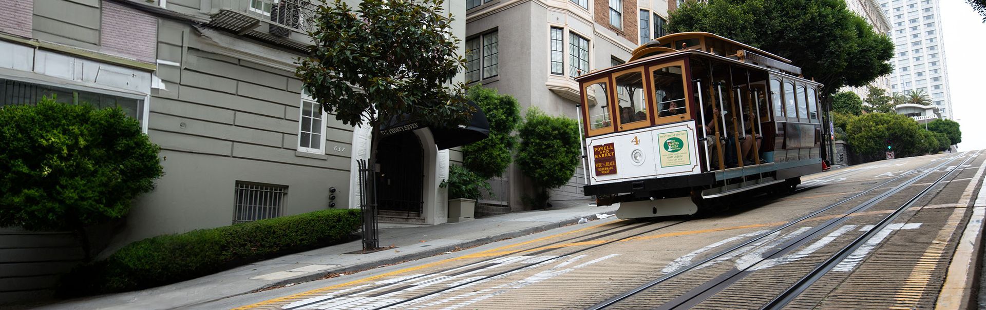 A trolley is going up a hill on a city street.