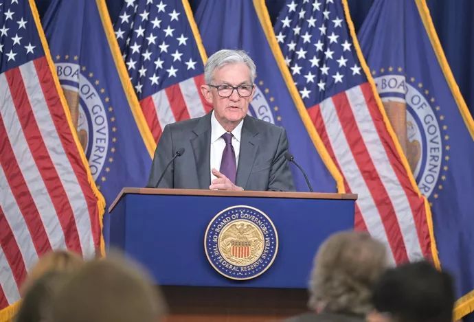 A man in a suit and tie is standing at a podium in front of american flags