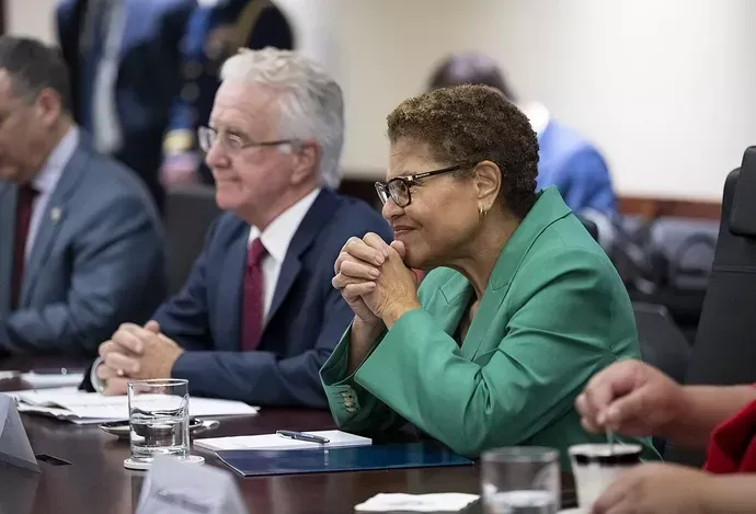 A woman in a green jacket is sitting at a table with other people.