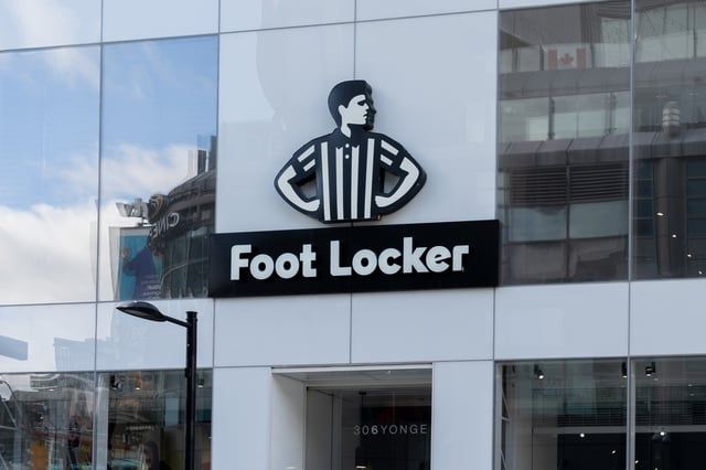 The front of a foot locker store with a man on it
