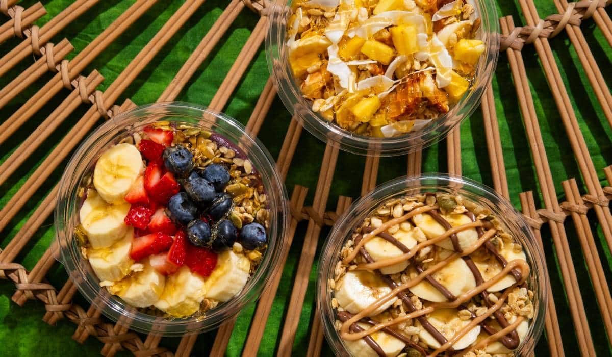 Three bowls of fruit are sitting on a wooden table.