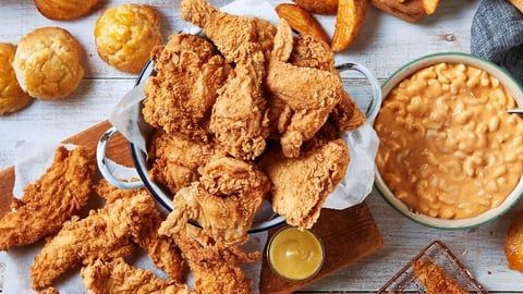 A table topped with fried chicken , macaroni and cheese , and biscuits.