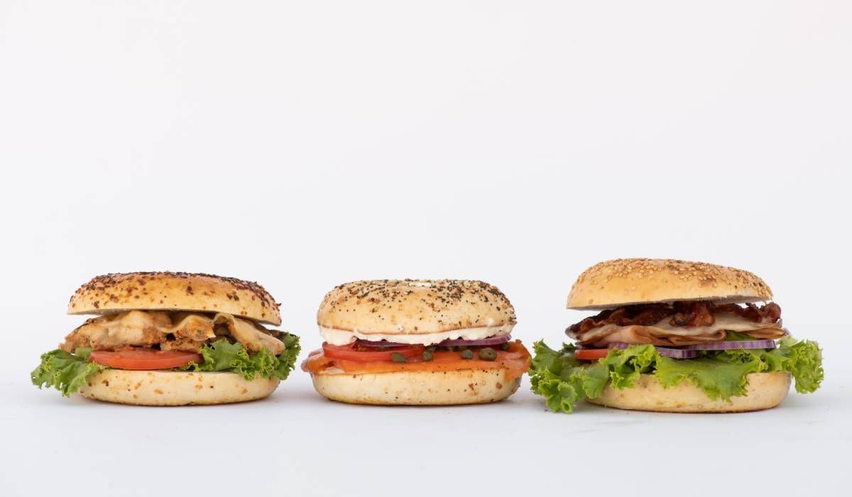 Three sandwiches are lined up in a row on a white surface.