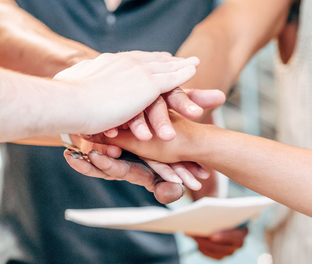 A group of people are putting their hands together in a huddle.