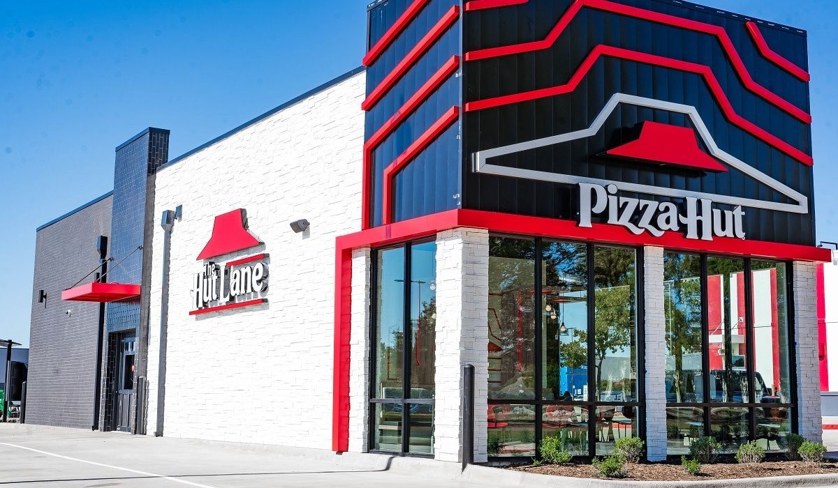 A pizza hut restaurant with a lot of windows and a red awning.