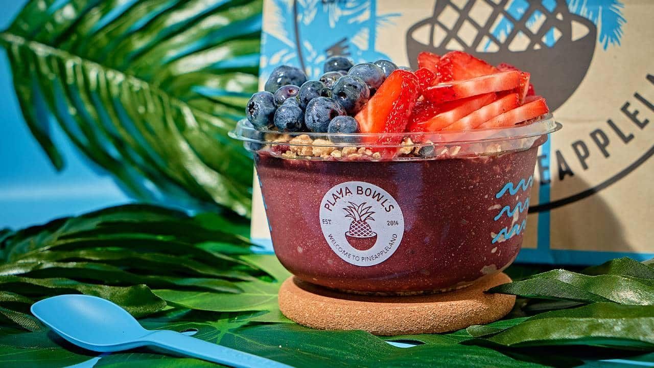 A bowl of acai bowl with blueberries and strawberries and a spoon.