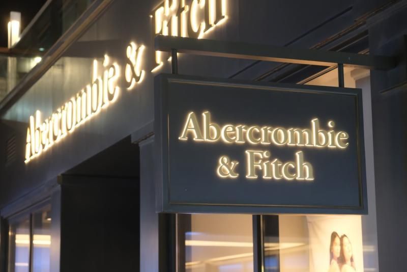A sign for abercrombie & fitch is lit up at night