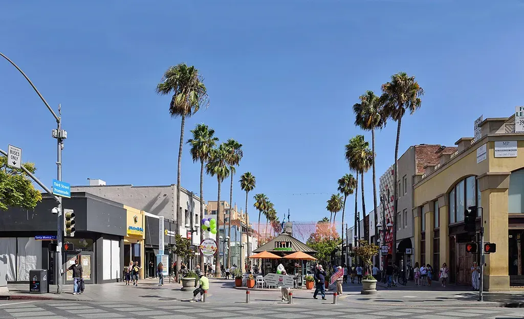 A city street with palm trees and buildings on a sunny day