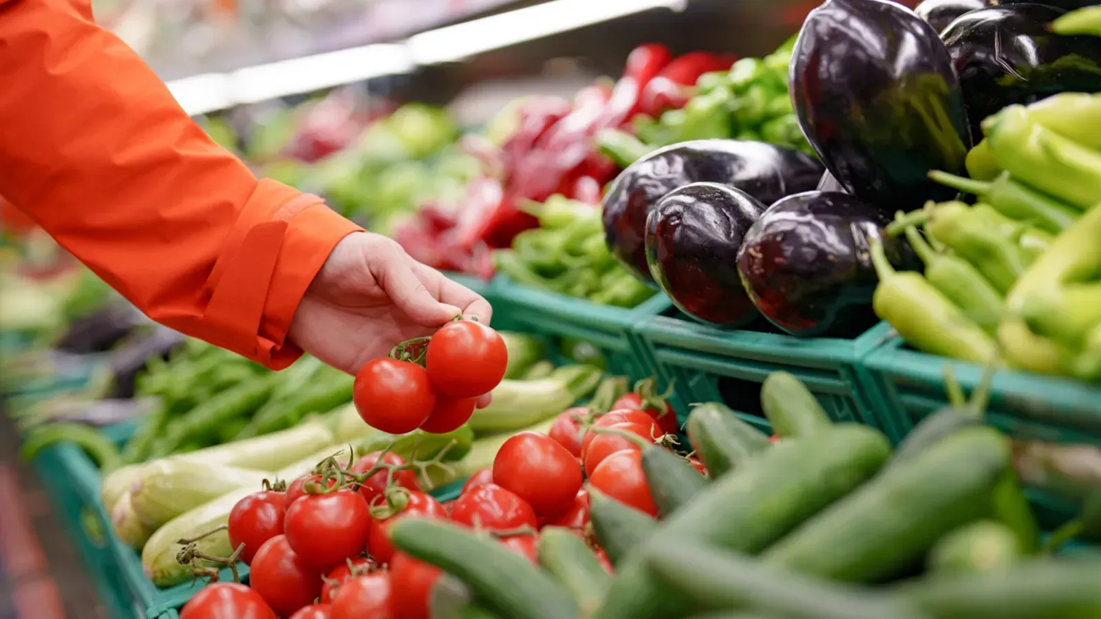 A person is picking tomatoes in a grocery store.