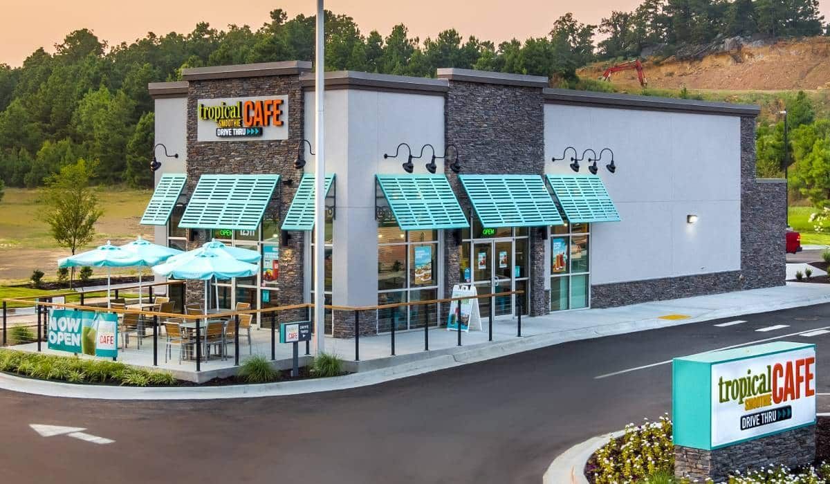 A fast food restaurant with umbrellas and tables in front of it.