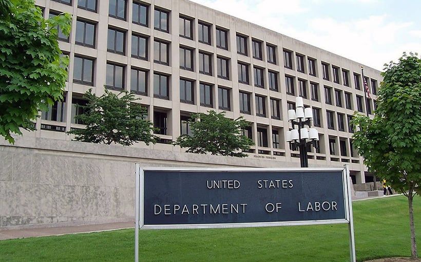 A sign for the united states department of labor is in front of a large building