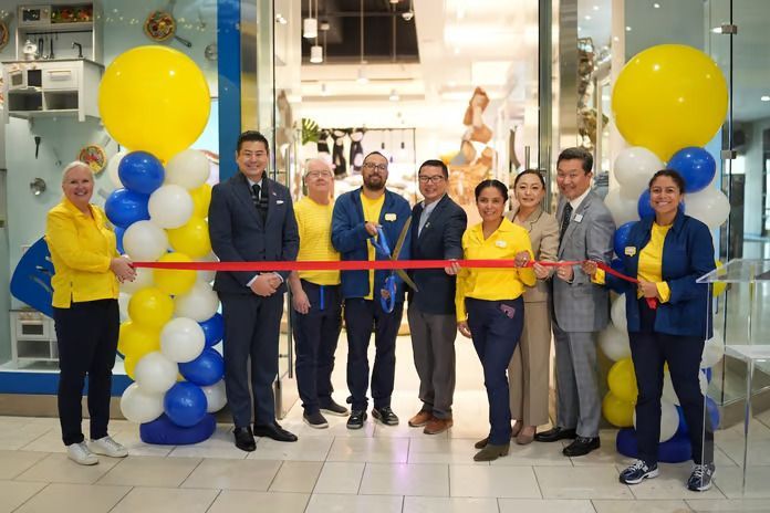 A group of people are standing in front of a store cutting a ribbon.