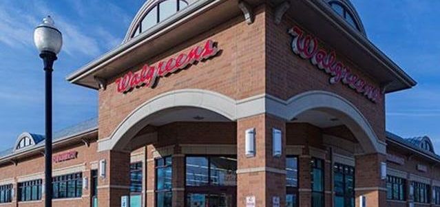 The front of a walgreens store with a street light in front of it.