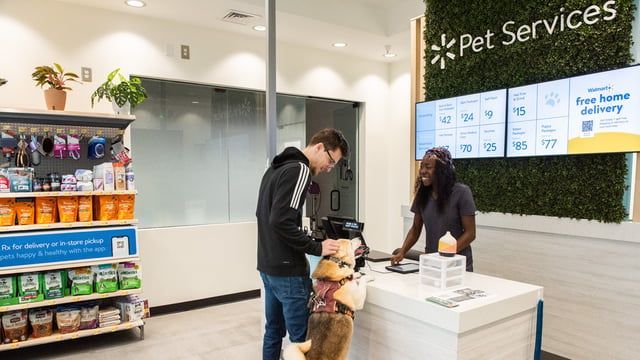 A man is standing next to a dog in a pet services store.