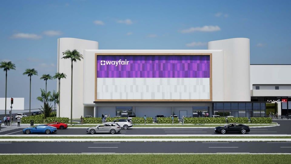 A green Publix Food & Pharmacy sign mounted on a white and beige building exterior against a blue sky.