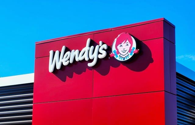 A red wendy 's restaurant with a blue sky in the background