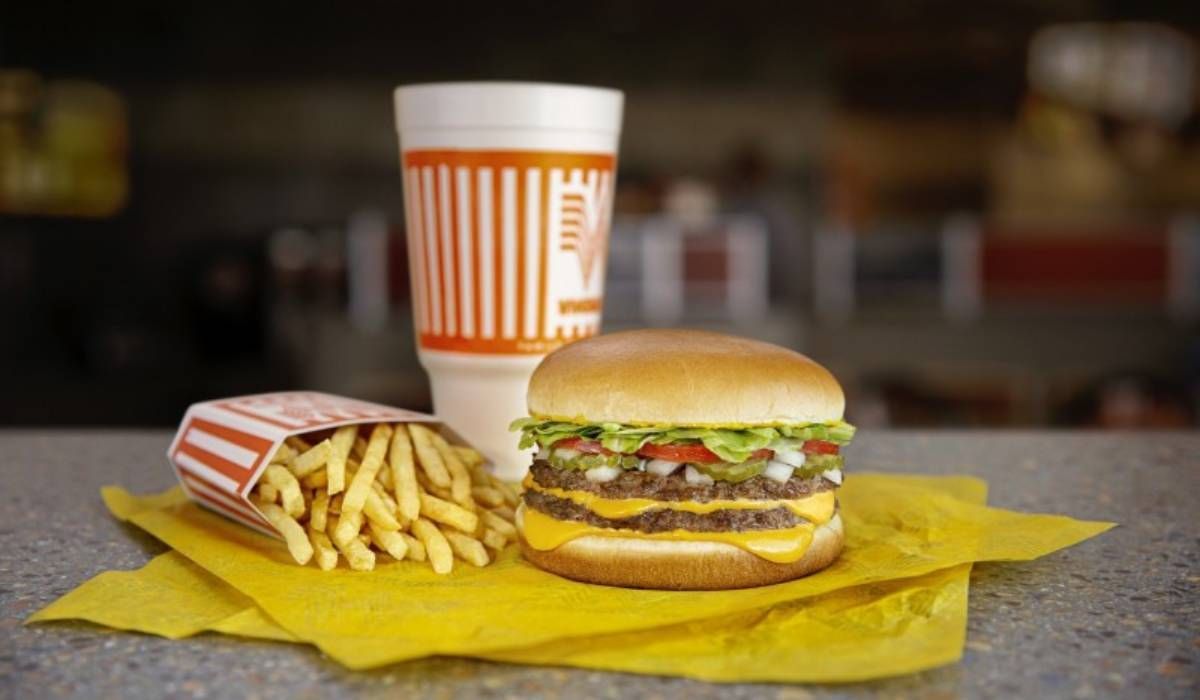 A hamburger , french fries and a drink are on a table.