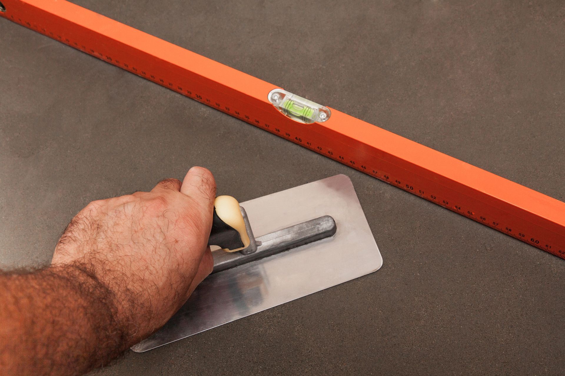 concrete contractor releveling a surface showing level and finishing trowel