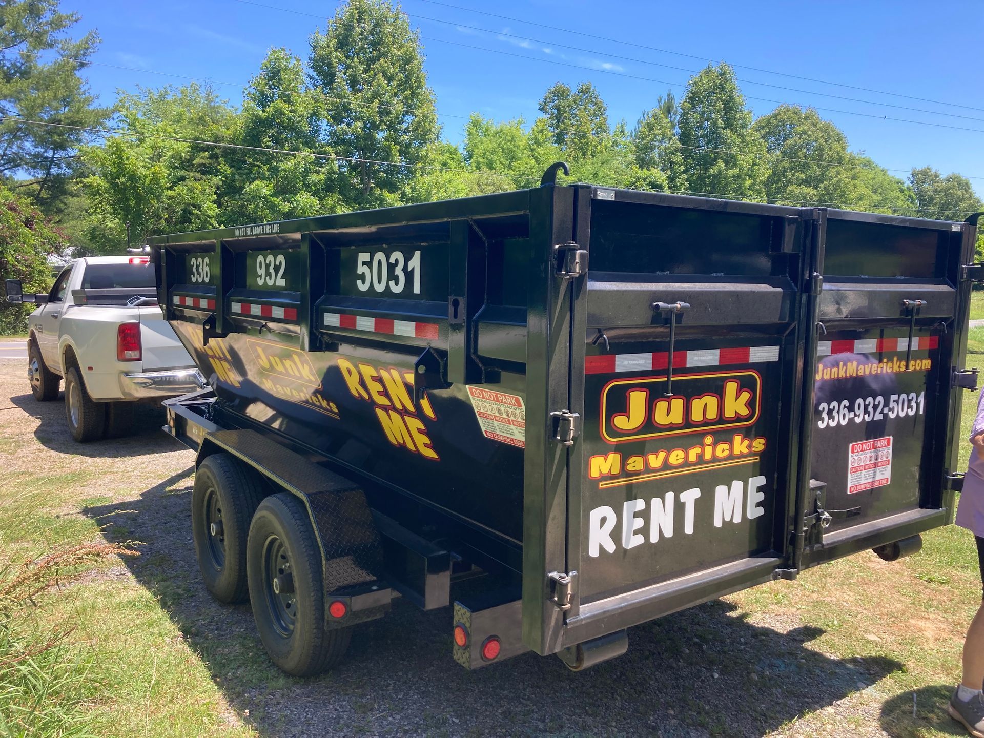 A dumpster trailer is parked next to a truck.