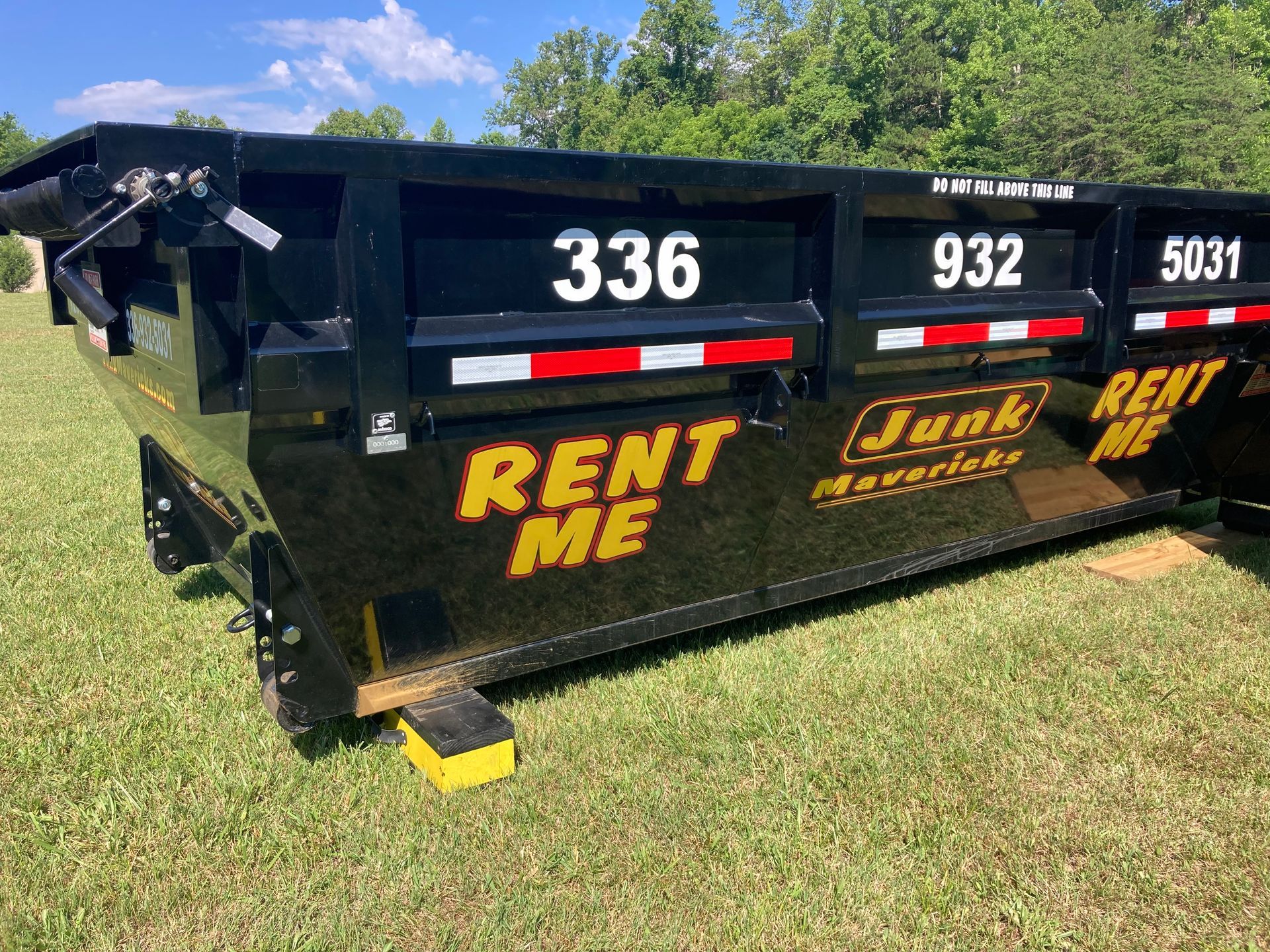 A man is standing in front of a dumpster that says junk mavericks