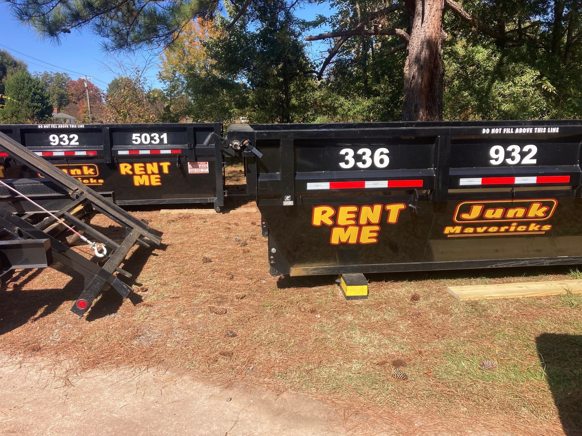Two dumpsters are parked next to each other in a yard.