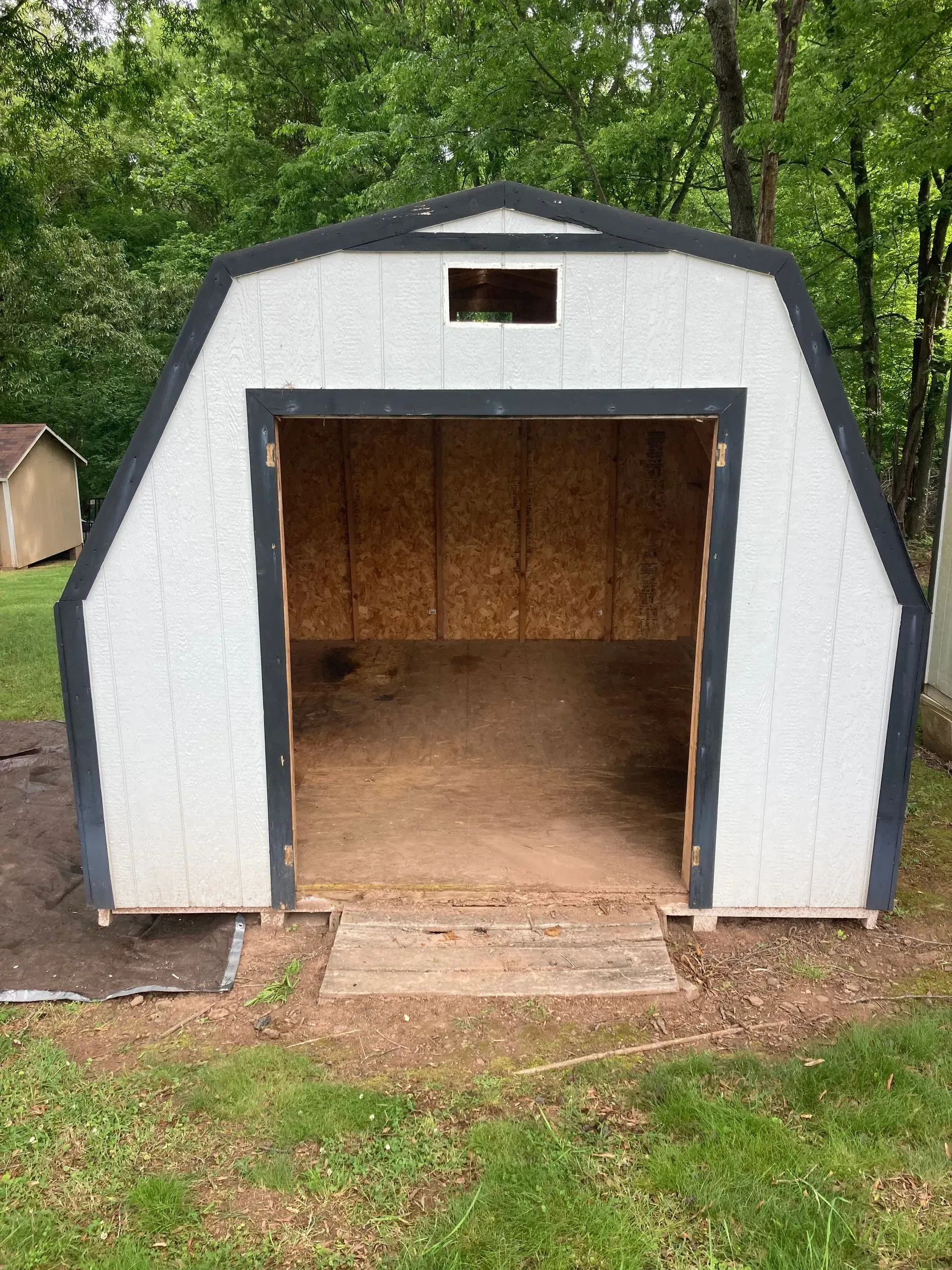 A pile of furniture is sitting in the grass in front of a house.