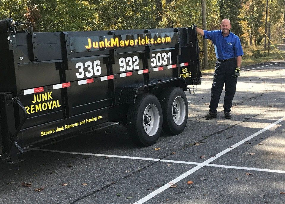 A dumpster filled with a lot of junk, including a couch and chairs.