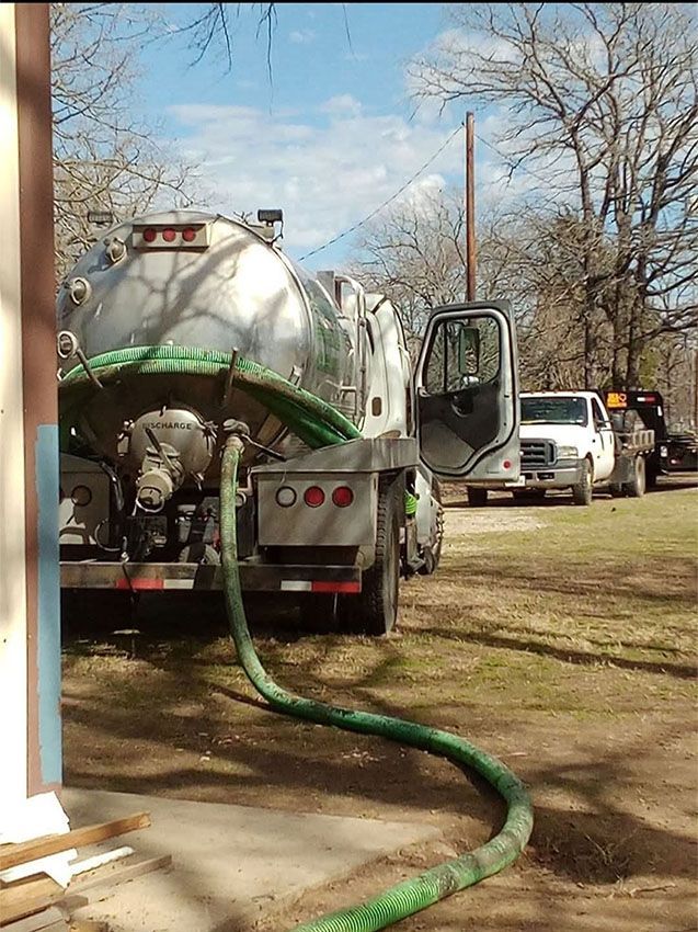 Woman in straw hat smiles, holding wine glass near a lake.