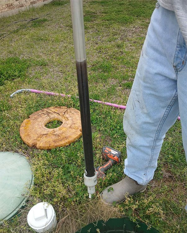 Woman in straw hat smiles, holding wine glass near a lake.