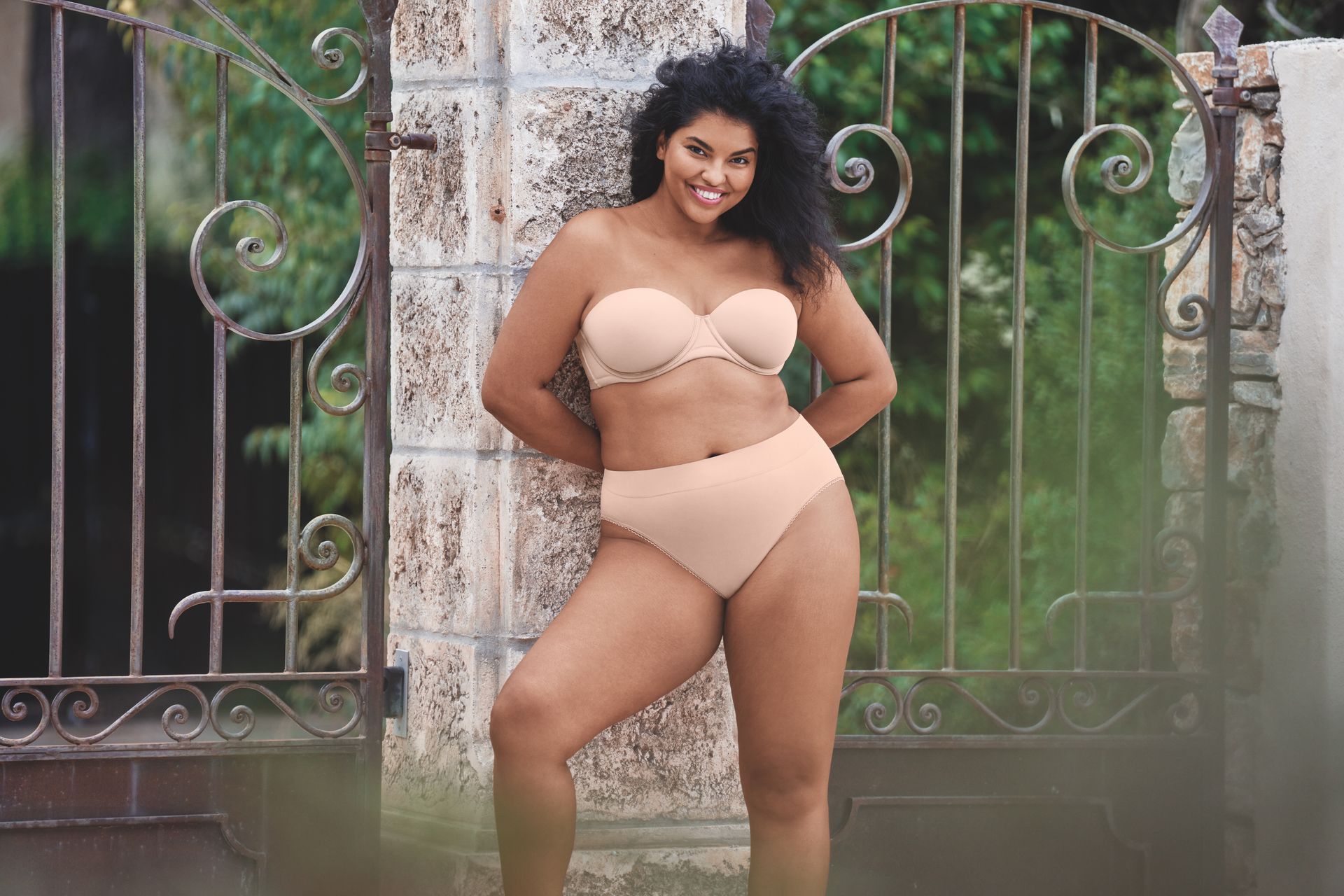 A woman in a bikini is standing in front of a gate.