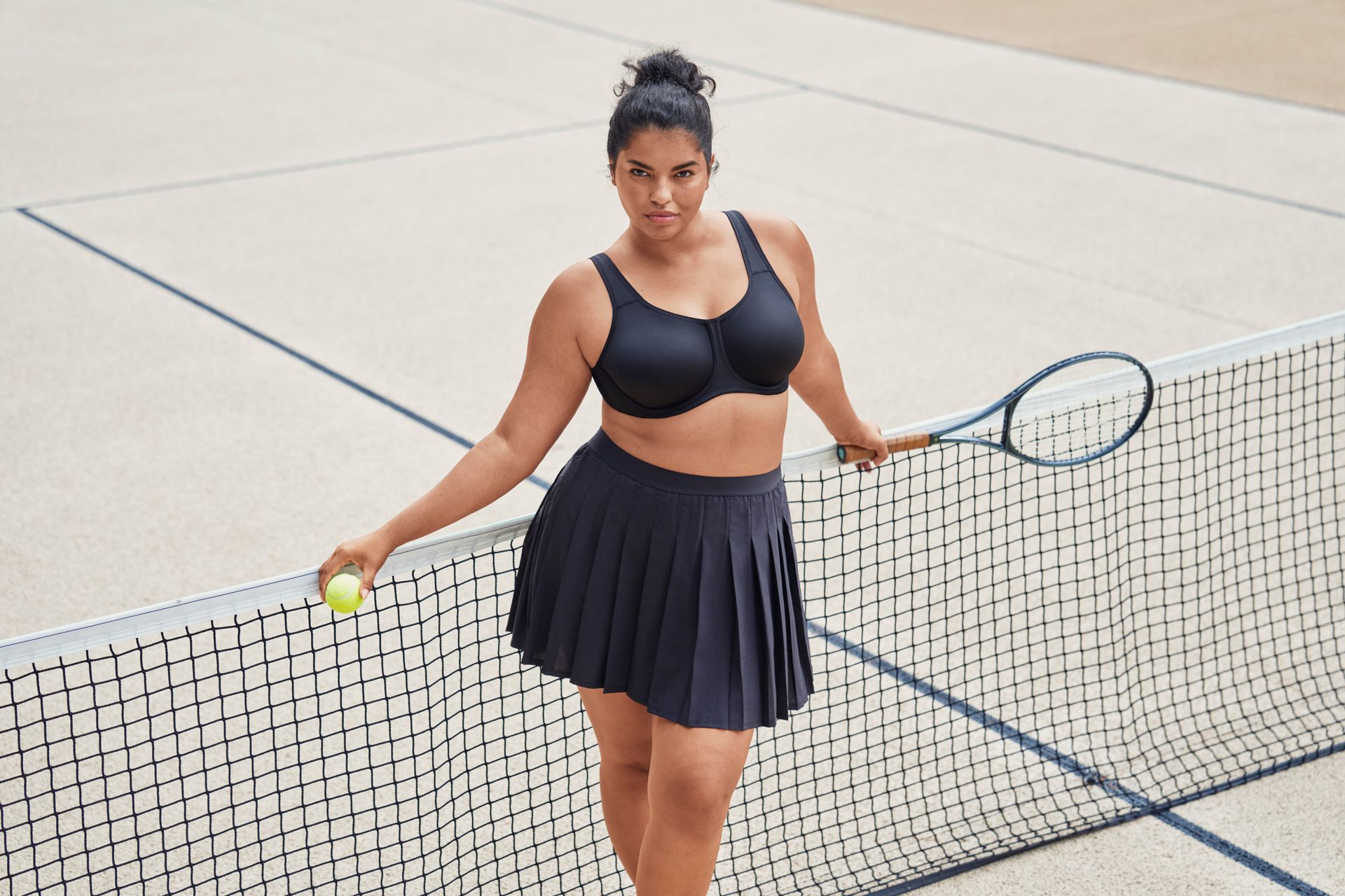 A woman is holding a tennis racket and a tennis ball on a tennis court.