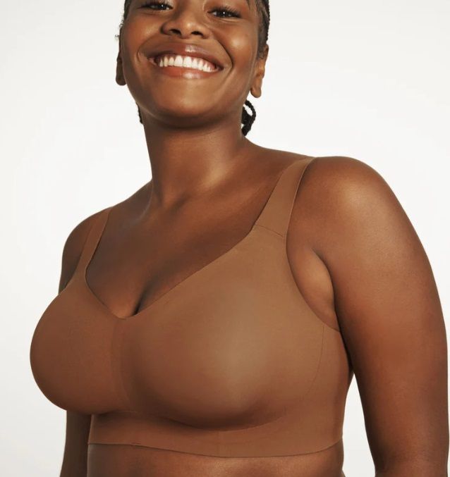 A woman in a brown bra is smiling for the camera