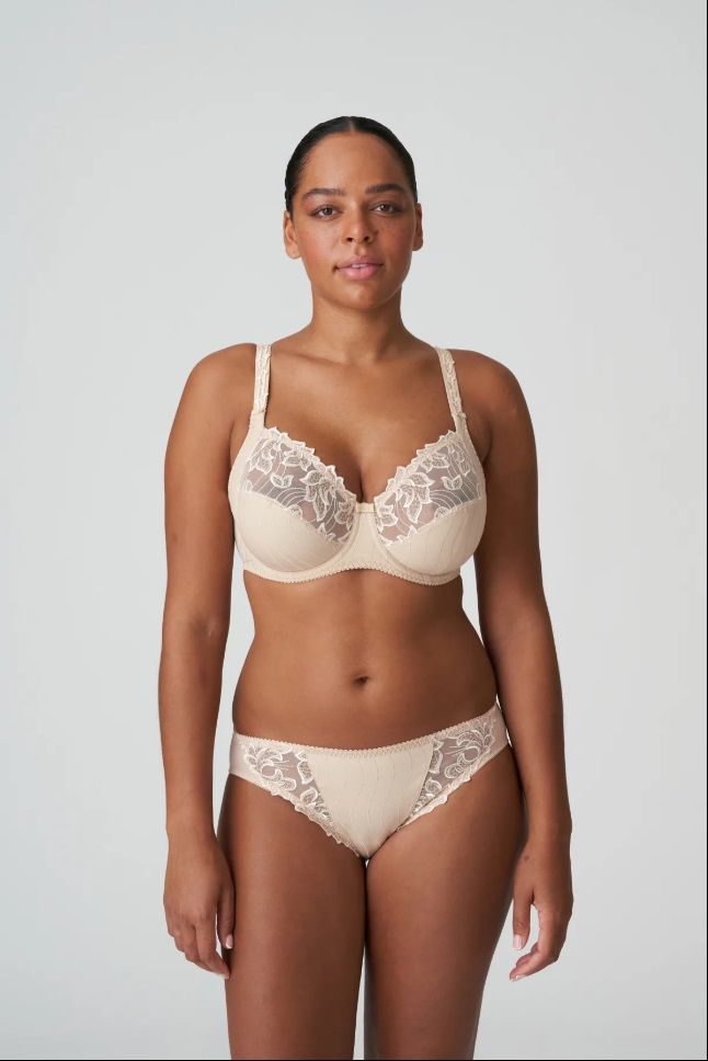 A woman wearing a bra and panties is standing in front of a white background.